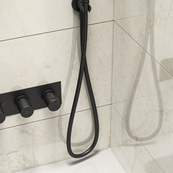 Detailansicht einer Badarmatur mit Brauseschlauch vor Fliesen