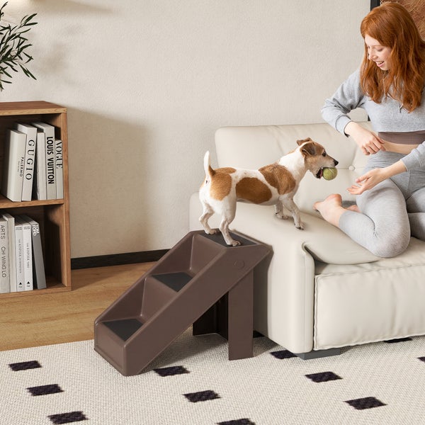 Dreistufige Hundetreppe aus Kunststoff an einem Sofa in einem hellen, aufgeräumten Wohnzimmer.