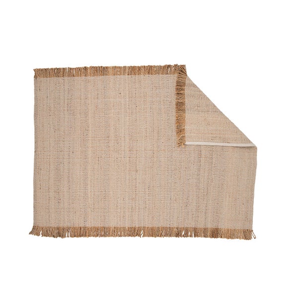 Dekorativer Teppich mit Fransen und einem Hocker mit Buch und Tasse