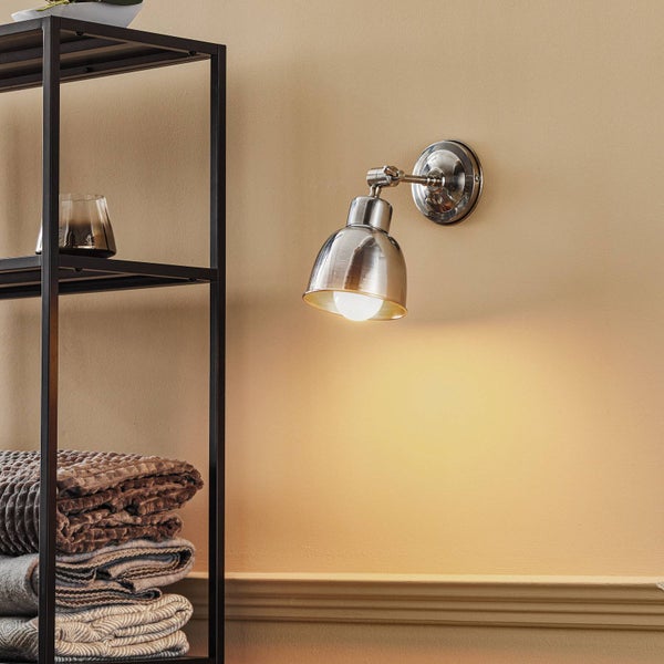 Wandleuchte neben einem Regal mit Textilien und einem Glas