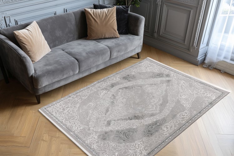 Rechteckiger Teppich mit ornamentalem Muster in einem modern eingerichteten Wohnzimmer mit Sofa und Parkettboden.