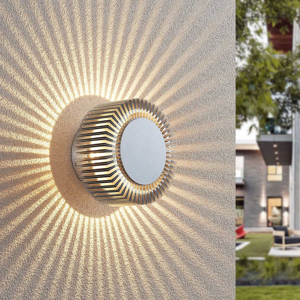 Runde LED Außenwandleuchte an einer strukturierten Wand mit strahlenförmigem Lichteffekt an einem modernen Gebäude.