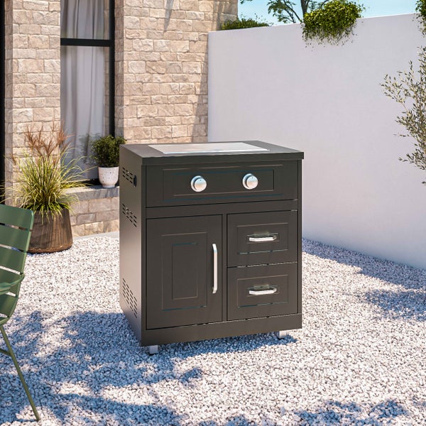 Moderne schwarze Außenküche mit Gaskochfeld, zwei Schubladen und einer Schranktür auf hellem Kies in einem sonnigen Garten.