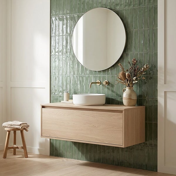 Modernes Badezimmer mit Waschtisch aus Holz, rundem Spiegel, Aufsatzwaschbecken und Wandfliesen in grüner Optik.