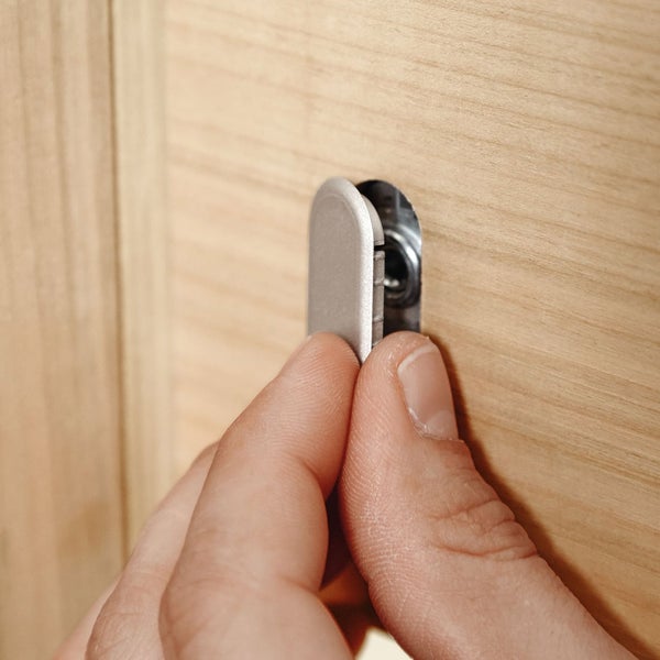Eine Person befestigt einen Möbelverbinder an einem Holzmöbelstück.