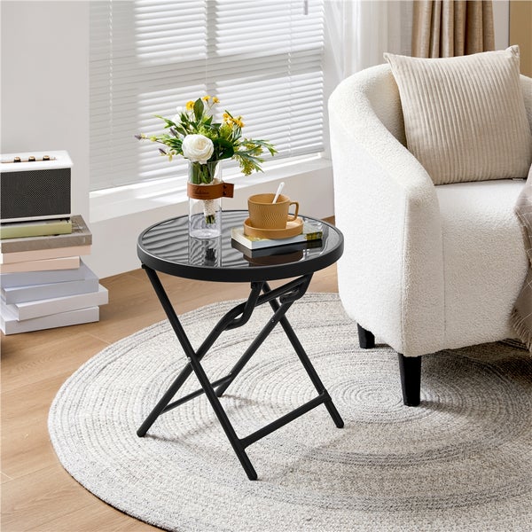 Runder, klappbarer Beistelltisch mit Glasplatte neben Sessel