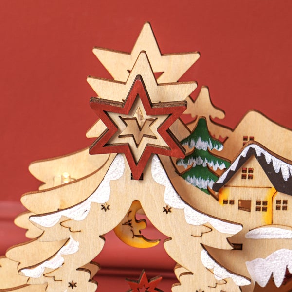 Weihnachtsdekoration aus Holz mit mehrschichtiger Winterszene aus Sternen, Häusern, Tannen und einer Mondsichel.