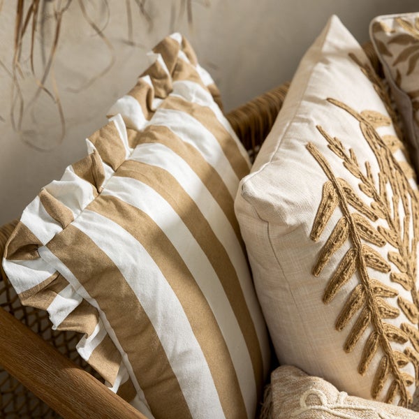 Dekorative Kissen mit Streifenmuster und Pflanzenmotiv in einem Korb.
