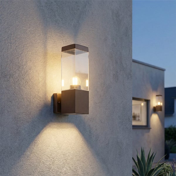 Moderne rechteckige Außenwandleuchte aus Glas und Metall montiert an einer grauen Wand mit warmweißem Lichtschein nach oben und unten.