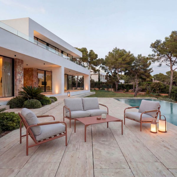 Moderne Lounge-Garnitur mit Metallgestell, bestehend aus Zweisitzer-Sofa, Sesseln und Tisch auf einer hellen, geräumigen Terrasse neben einem Pool.