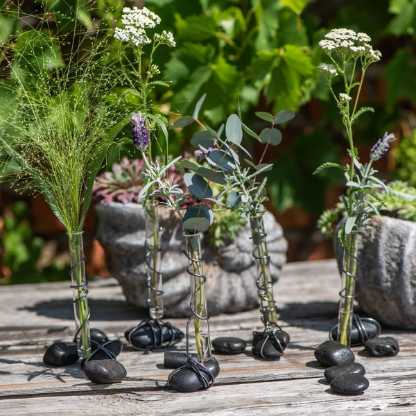Arrangement mit Gras, Lavendel, Schafgarbe und Eukalyptus in Glasvasen auf Holz