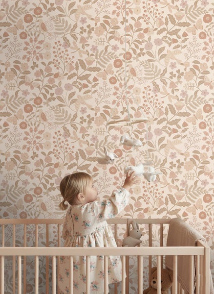 Tapete mit Blumen- und Vogelmuster im Kinderzimmer, ein Kind im Gitterbett greift nach einem Mobile.
