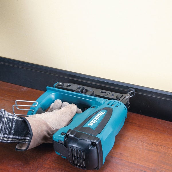 Makita Nagelgerät bei der Befestigung einer Fußleiste an einer Wand.
