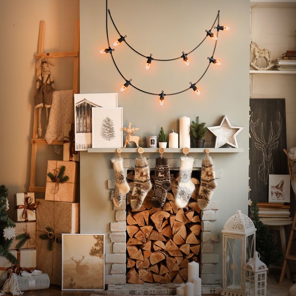 Festlich dekorierter Kamin mit Lichterkette, Weihnachtssocken und Geschenken im skandinavischen Stil