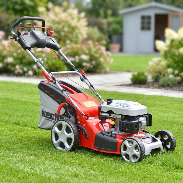 Roter Rasenmäher auf Rasen vor Gartenhaus