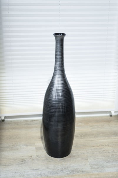 Hohe, schlanke Bodenvase mit feiner horizontaler Strukturierung auf hellem Holzboden.