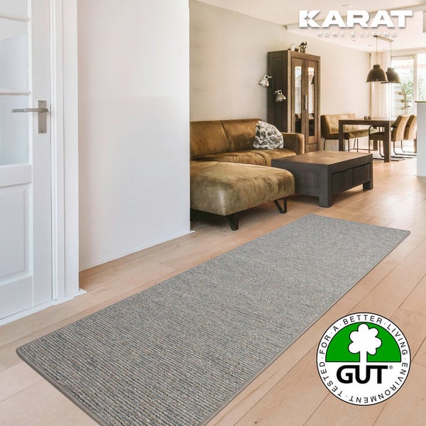 Strukturierter Teppichläufer auf Holzfußboden in hellem Wohnzimmer. Karat Home und Living Logo. Siegel für umweltfreundliche Teppichböden.
