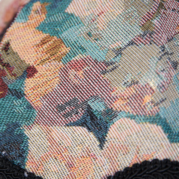 Detailaufnahme eines gewebten Stoffes mit floralem Muster und strukturierter Oberfläche.