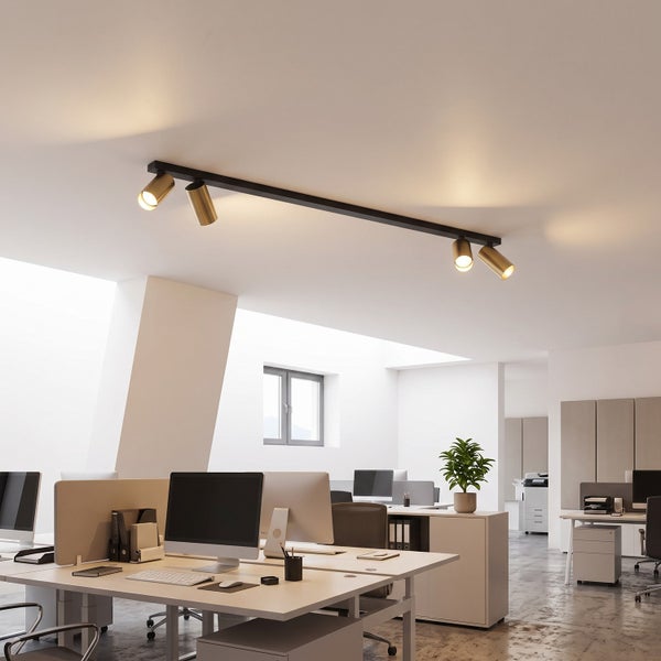 Moderne Deckenleuchte mit vier verstellbaren Strahlern an einer Schiene in einem hellen, offen gestalteten Büro mit Computerarbeitsplätzen.