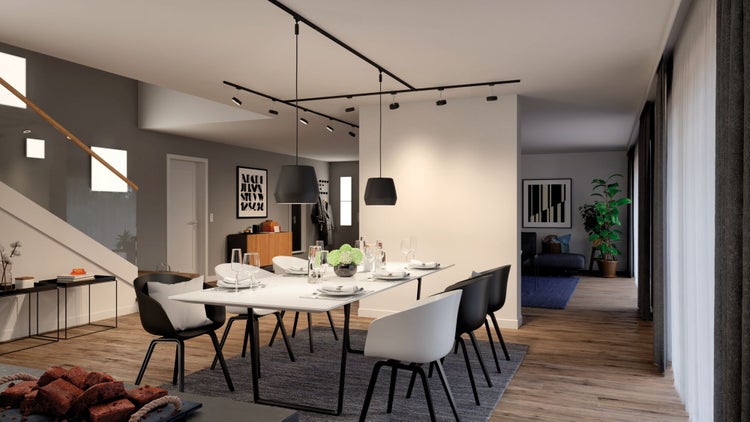 Modernes Esszimmer mit weißem Esstisch, schwarz-weißen Stühlen und einem schwarzen Schienensystem mit Pendelleuchten.