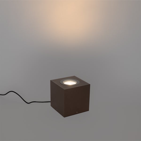 Würfelförmige Außenleuchte in Dunkelbraun mit nach oben gerichtetem Lichtstrahl und schwarzem Anschlusskabel.