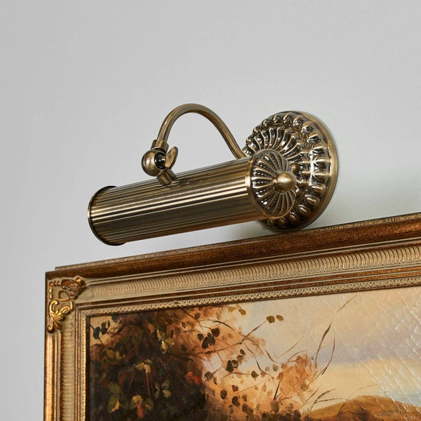 Messingfarbene Bilderleuchte über einem gerahmten Gemälde