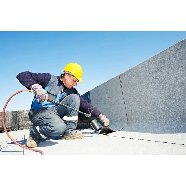 Dachdecker verlegt Bitumenschweißbahnen auf einem Flachdach mit einem Gasbrenner.