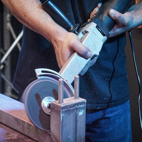 Ein Mann schneidet Metall mit einem Winkelschleifer.