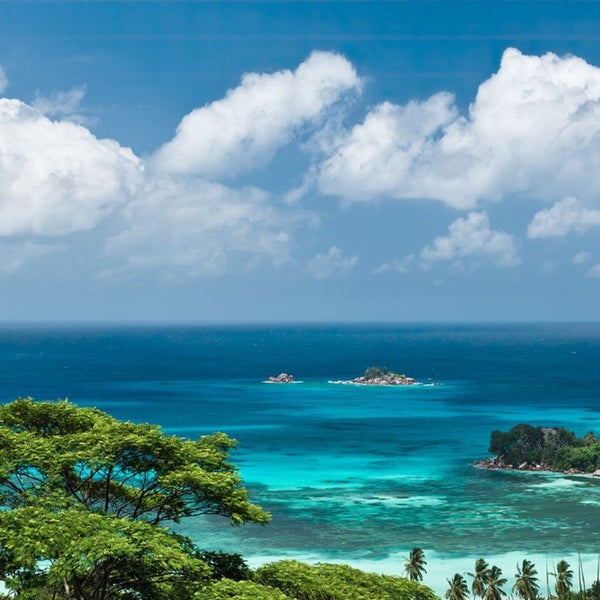 Landschaft mit Meerblick, tropischer Vegetation und kleinen Inseln unter einem bewölkten Himmel