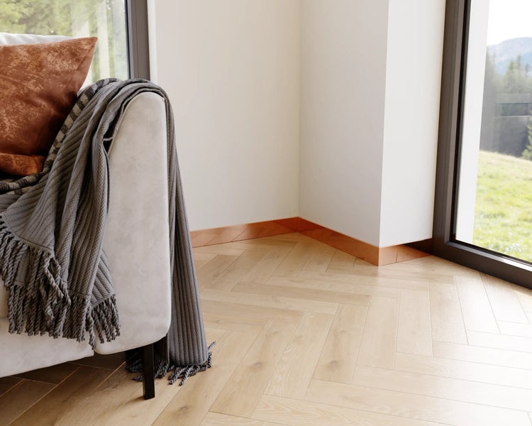 Innenraumszene mit Parkettboden in Fischgrätmuster, Sockelleisten und einem Sofa mit Kissen und Decke