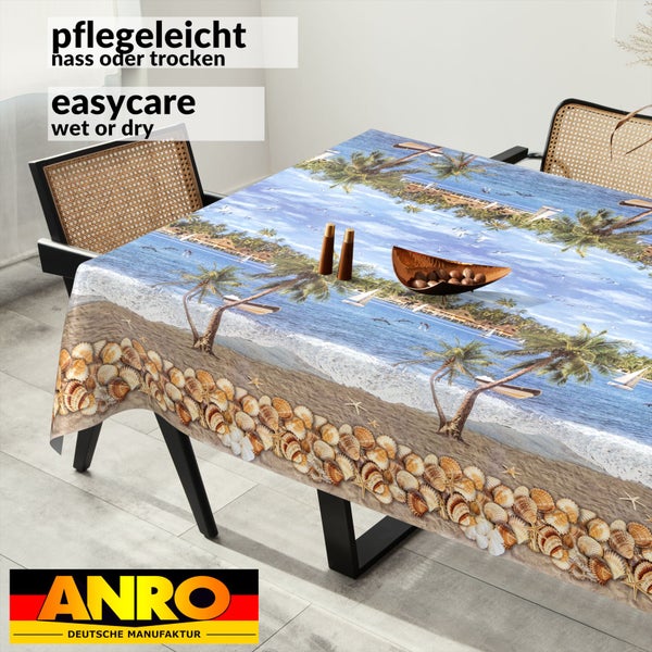 Pflegeleichte Tischdecke mit tropischem Strandmotiv, Palmen und Muscheln auf einem Esstisch in einem hellen, modernen Esszimmer. ANRO Logo.