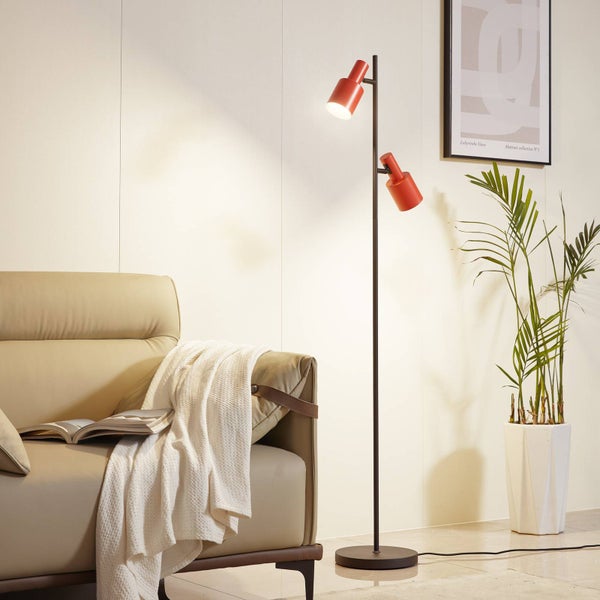 Stehlampe mit zwei Leuchten neben einem Sofa in einem Wohnzimmer.