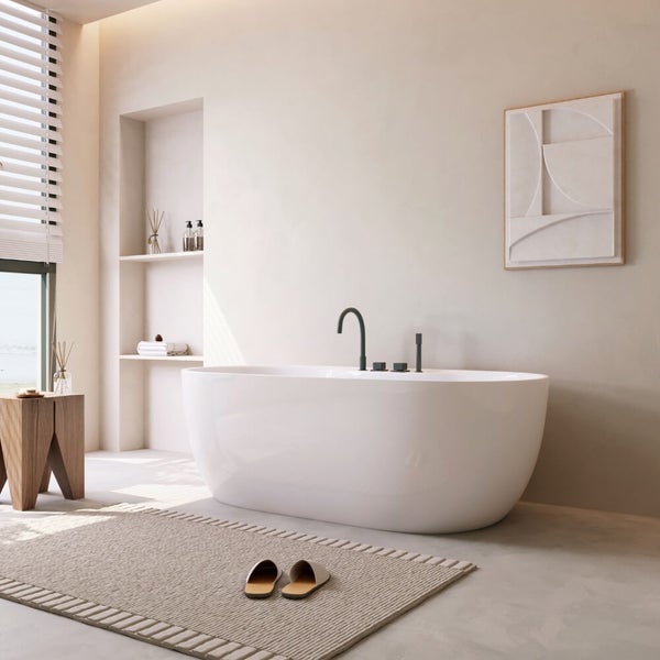 Freistehende Badewanne in einem hellen, modernen Badezimmer mit Wandnische, Holzhocker und Badematte.