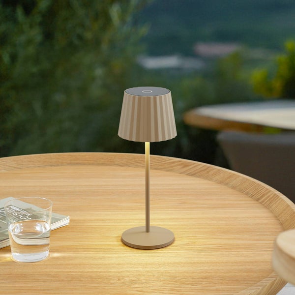 Moderne kabellose LED-Tischleuchte für den Außenbereich mit gefaltetem Schirm auf einem runden Holztisch.
