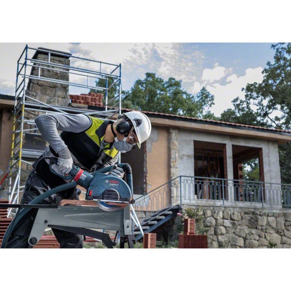 Ein Bauarbeiter schneidet mit einer Steintrennsäge einen Ziegelstein auf einer Baustelle.