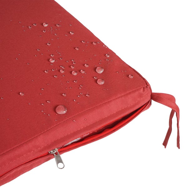 Wasserabweisendes rotes Sitzkissen mit Reißverschluss, Bindebändern und Wassertropfen auf dem Stoff.