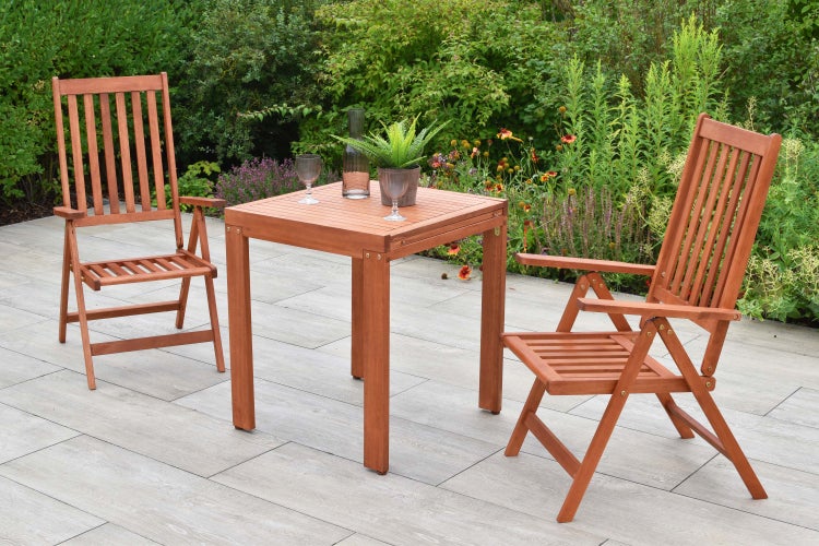 Gartenszene mit einem Holztisch, zwei Stühlen, Pflanzen und Gläsern