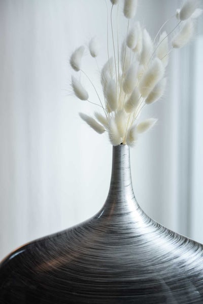 Vase aus gebürstetem Metall mit getrocknetem Lagurus-Gras.