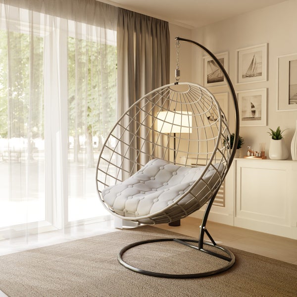 Ein freistehender Hängesessel mit Metallgestell und komfortablem Polster in einem hellen, modern eingerichteten Wohnzimmer vor einer Fensterfront.