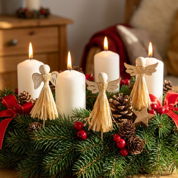 Adventskranz mit vier brennenden Stumpenkerzen, Holzengeln, Tannenzapfen, roten Beeren und roter Schleife als festliche Weihnachtsdekoration.