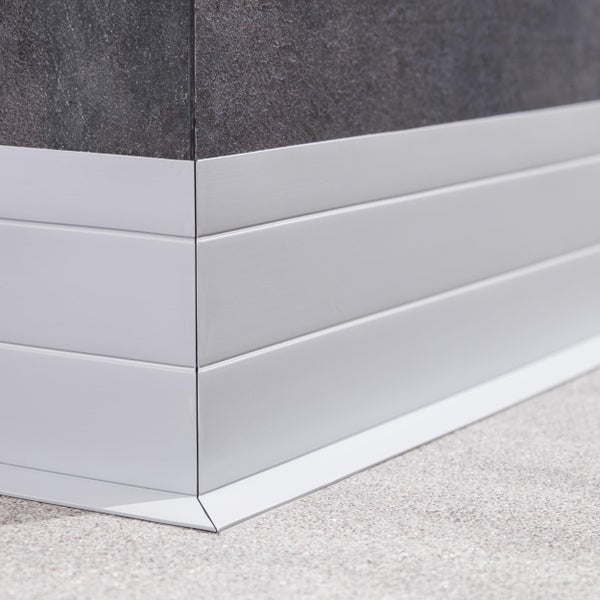 Moderne Sockelleiste aus Metall in L-Form an einer Wand mit dunklen Fliesen