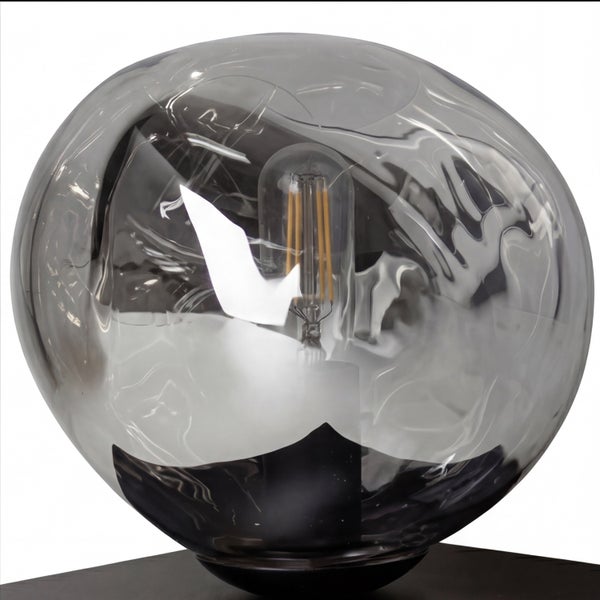 Kugelförmige Tischleuchte aus rauchfarbenem, unregelmäßigem Glas mit sichtbarem LED-Leuchtmittel.