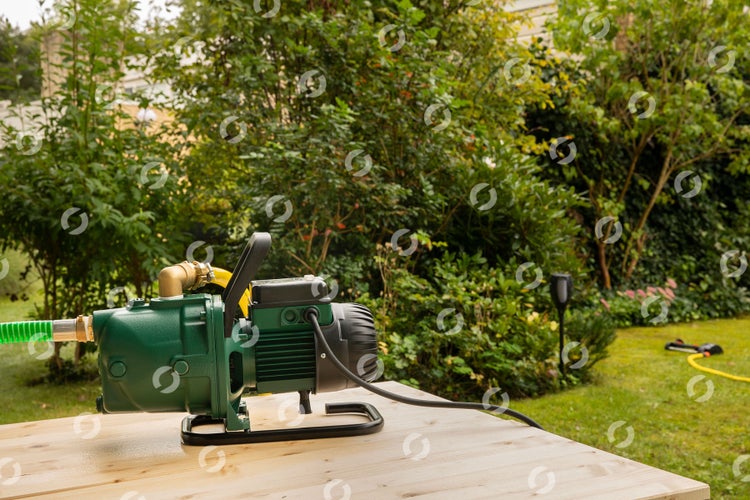 Garten Szene mit einer Gartenpumpe auf einem Holztisch vor einem grünen Garten