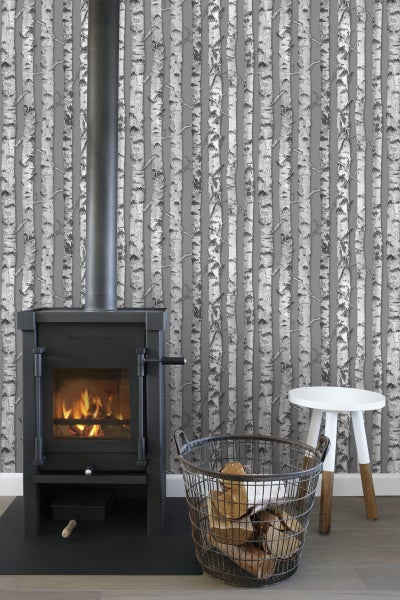 Wohnraum mit Kaminofen, Holzkorb und Birkenwaldtapete