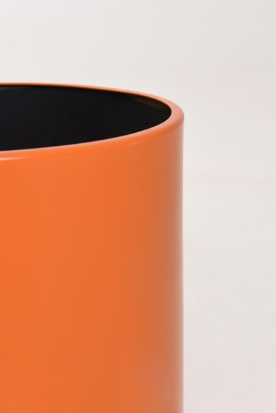 Detailansicht eines zylindrischen orangefarbenen Pflanzentopfs mit glatter Oberfläche und schwarzer Innenseite.