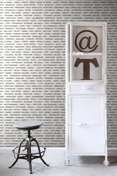 Dekoratives Regal mit Rollen und ein Hocker vor einer gemusterten Wand