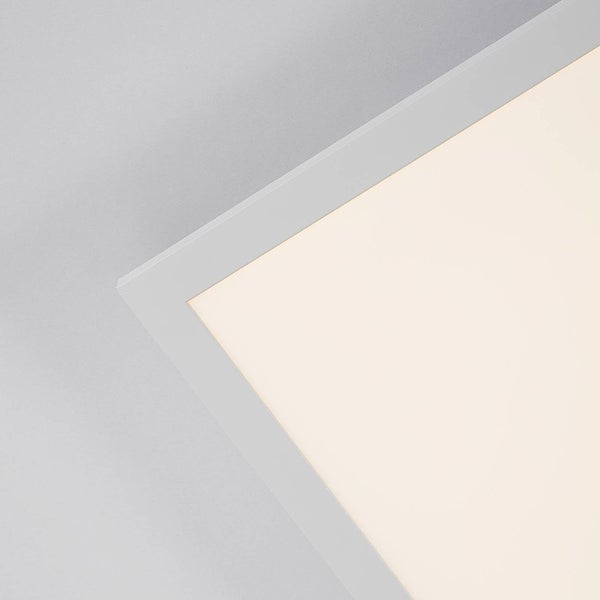 Nahaufnahme einer Ecke eines flachen LED-Panels für die Decke mit schmalem weißem Rahmen und warmweißer Beleuchtung.