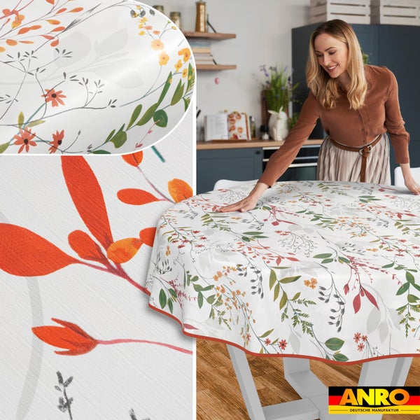 Eine Frau legt eine runde Tischdecke mit Blumenmuster auf einen Küchentisch. Nahaufnahmen zeigen das florale Design. ANRO Logo.