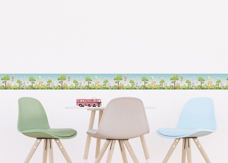 Zimmer mit einer Bordüre mit Bäumen, Hasen, Teddys und Luftballons über einem Tisch und Stühlen