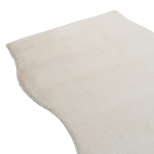 Weicher Kunstfellteppich mit welligem Rand und flauschiger Textur.